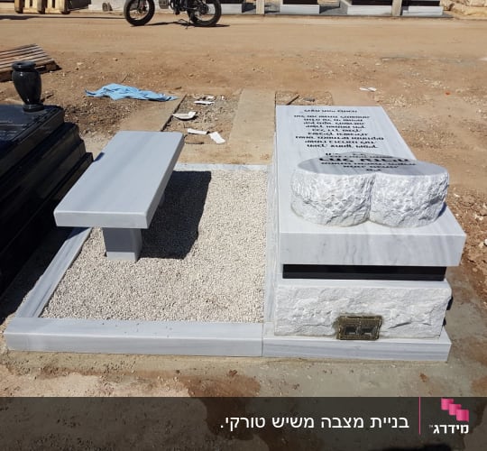מצבה עם כיתוב ואבנים, ספסל ליד